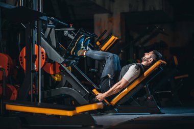 young man has legs workout in modern gym