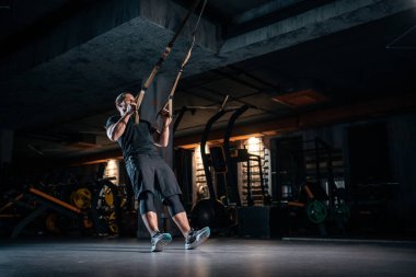 young man has crossfit workout with trx in modern gym