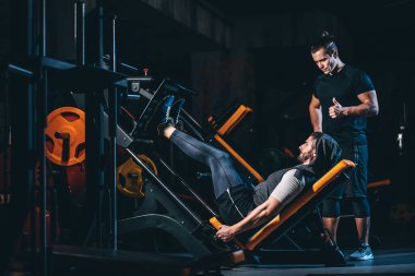 young man has workout with personal trainer in modern gym