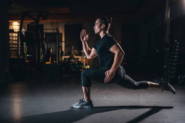 Genç adam jimnastik salonunda paten ve ağırlık egzersizi yapıyor.