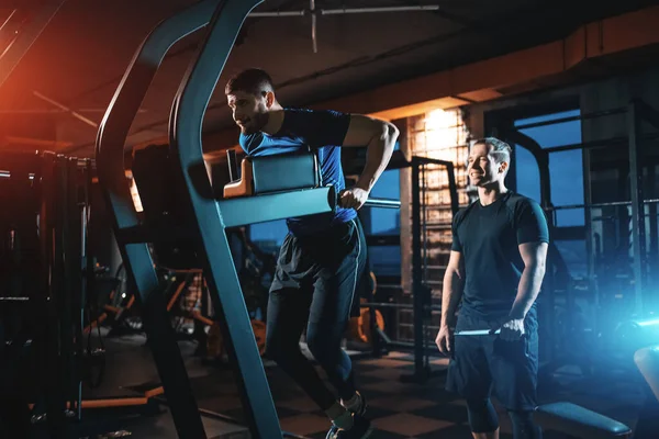 Young man has workout with personal trainer in modern gym — Stock Fotó