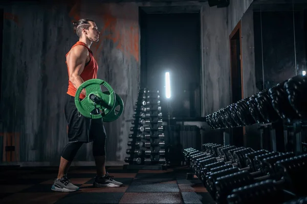 Atleta joven tiene entrenamiento físico con barra en el gimnasio moderno —  Fotos de Stock