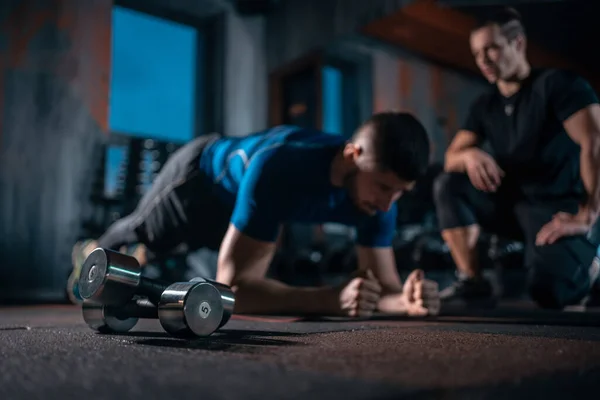 Young man has workout with personal trainer in modern gym — Stock Fotó