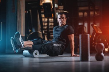 Genç adam jimnastik salonunda paten ve ağırlık egzersizi yapıyor.