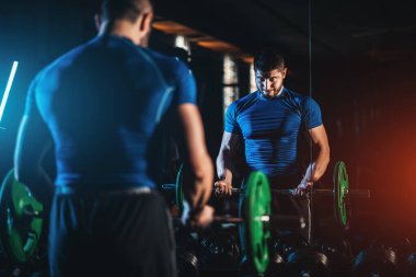 young athlete has physical workout with barbell in modern gym