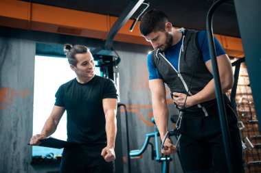 young man has workout with personal trainer in modern gym