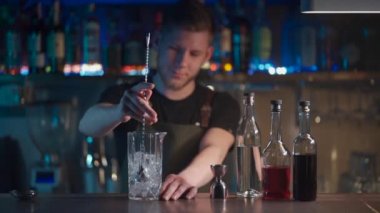 Barmen klasik negroni kokteylini rom ve buzla karıştırıyor.