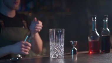 Barmen klasik negroni kokteylini rom ve buzla karıştırıyor.