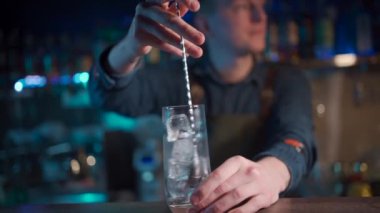Barmen modern cin tonik kokteylini buzla karıştırıyor.