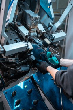 Ayakkabı fabrikasında otomatik makinelerle çalışan bir adam.