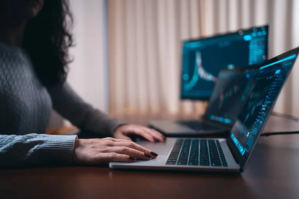 Comerciante femenino joven con el ordenador portátil y la pantalla mirando gráficos de stock — Foto de Stock