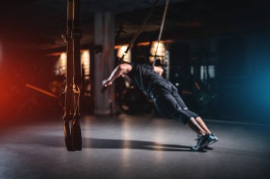 young man has crossfit workout with trx in modern gym