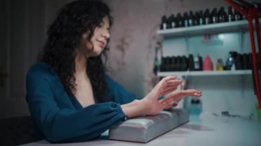 Güzel bir kadın manikür ve ojeye bakıyor.