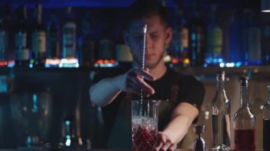 Barmen klasik negroni kokteylini rom ve buzla karıştırıyor.