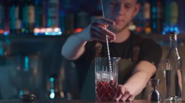 Barmen klasik negroni kokteylini rom ve buzla karıştırıyor.