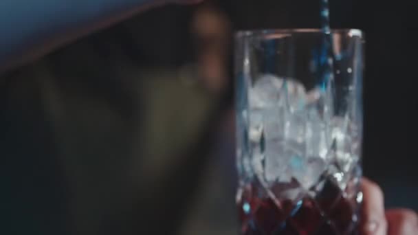 バーテンダーは古典的なネグローニカクテルとラム酒と氷を混ぜて — ストック動画