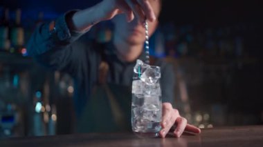 Barmen modern cin tonik kokteylini buzla karıştırıyor.