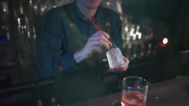 Barmen viski ve portakallı geleneksel kokteyl hazırlıyor.