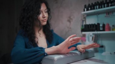 Güzel bir kadın manikür ve ojeye bakıyor.