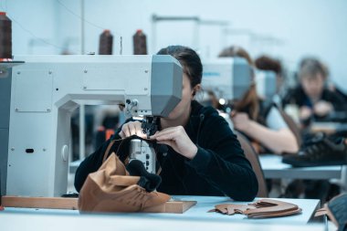 Kadın ayakkabı fabrikasında dikiş makinesi ile çalışıyor.