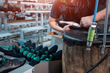 Ayakkabı fabrikasında otomatik makinelerle çalışan bir adam.