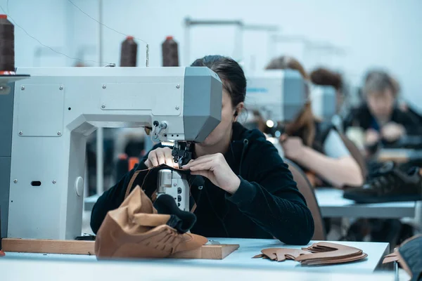 Жінка працює з швейними машинами на взуттєвій фабриці — стокове фото