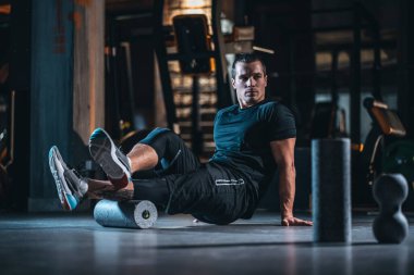 Genç adam jimnastik salonunda paten ve ağırlık egzersizi yapıyor.