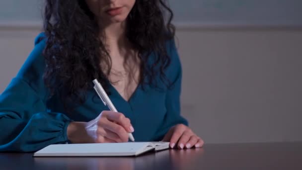 Encaracolado morena mulher fazendo notas na sala de aula da escola — Vídeo de Stock