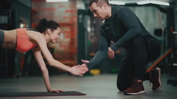 Entrenador personal con mujer fitness haciendo ejercicio en el gimnasio — Vídeos de Stock
