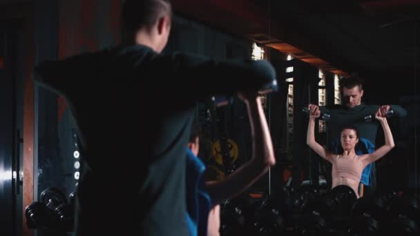 Personal trainer com mulher fitness exercitando com halteres no ginásio — Vídeo de Stock