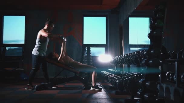 ジムでダンベルと運動するフィットネス女性のパーソナルトレーナー — ストック動画