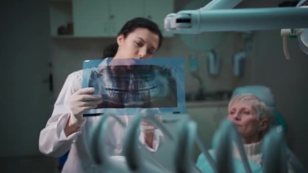专业牙医女性向病人展示全景口腔X光图像 — 图库视频影像