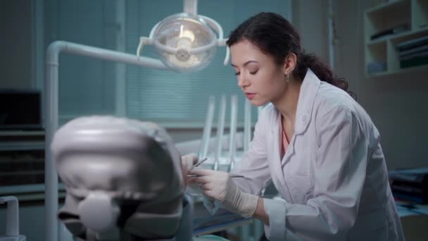 Güzel esmer kıvırcık kadın dişçi modern klinikteki hastayı tedavi ediyor. — Stok video
