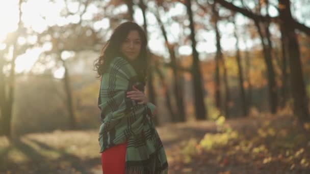 Mooi krullend brunette vrouw wandelen in de herfst park en glimlachen — Stockvideo