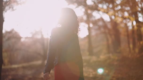 Mooi krullend brunette vrouw wandelen in de herfst park en glimlachen — Stockvideo