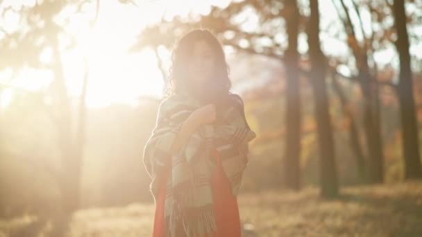 Mooi krullend brunette vrouw wandelen in de herfst park en glimlachen — Stockvideo