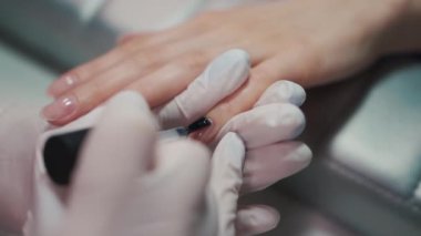 Manikür sanatçısı fırça ve aletlerle tırnak cilası yapıyor