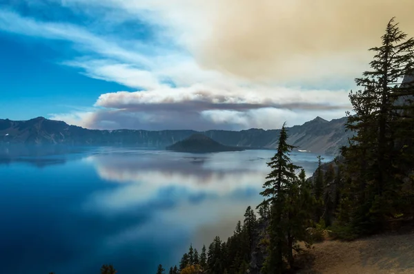 Кратерне озеро з хмарою диму з прилеглої лісової пожежі — стокове фото