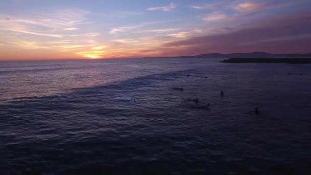 Surfers in het water tijdens een mooie zonsondergang luchtfoto — Stockvideo