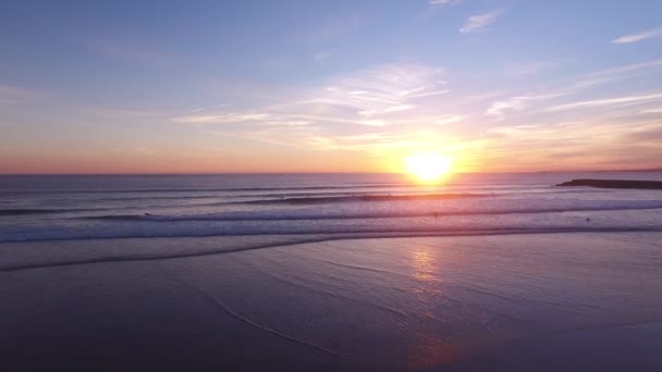 Серфингисты в воде во время прекрасного захода солнца — стоковое видео