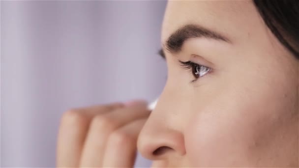 Maquillaje artista pinta sombras ojos de hermosa morena joven primer plano — Vídeo de stock