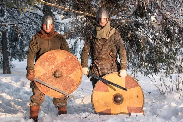 Two warriors in historical armor in a winter forest