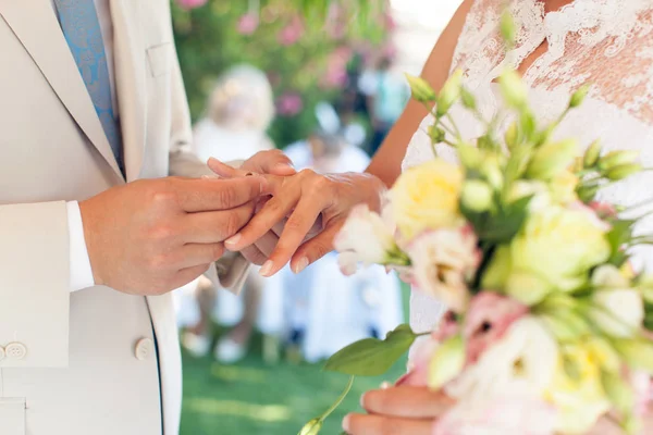 O noivo usa um anel no dedo da noiva em um casamento — Fotografia de Stock