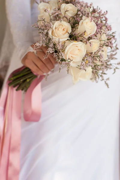 Bruid in witte jurk houdt een bruiloft boeket rozen — Stockfoto