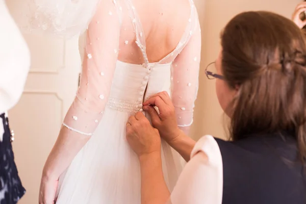 Vrouw helpt de bruid om te proberen op een trouwjurk — Stockfoto