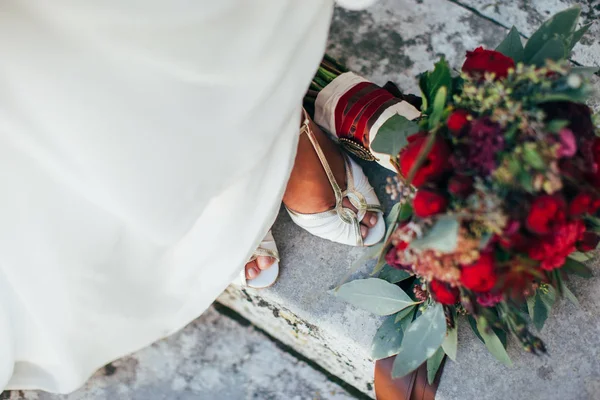 De bruids boeket rood-groene aan de voeten van de bruid — Stockfoto