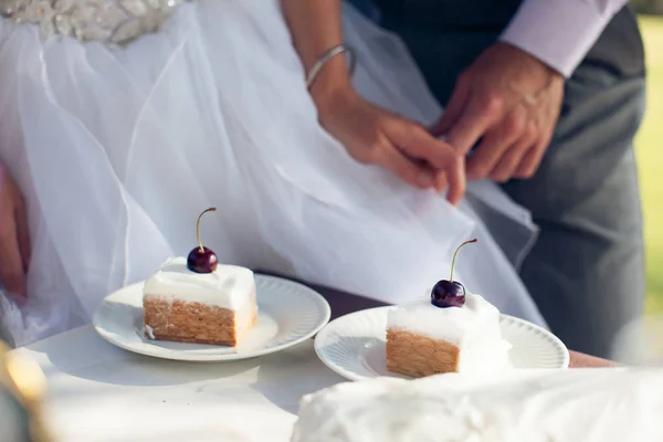 En bit av bröllopstårta framför bruden och brudgummen — Stockfoto