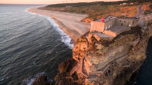 Vista aérea del océano, la playa norte y el faro nazarí al atardecer, Portugal — Foto de Stock