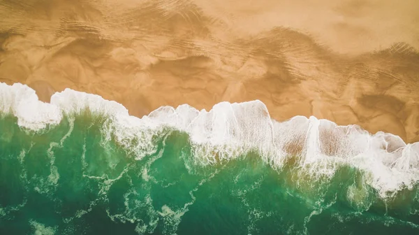 Belle onde oceaniche e spruzzi su una spiaggia di sabbia a Nazar, Portogallo. Vista aerea Foto Stock Royalty Free