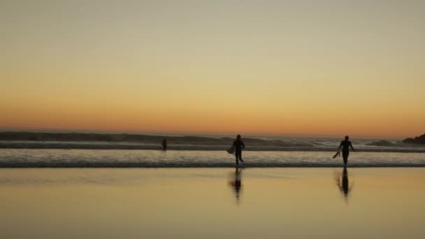 Surfers bij zonsondergang in de buurt van de Atlantische Oceaan, Costa de Caparica, Portugal — Stockvideo